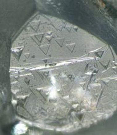 Etched trigons on the surface of the diamond crystal 