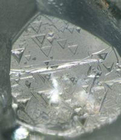 Etched trigons on the surface of diamonds 