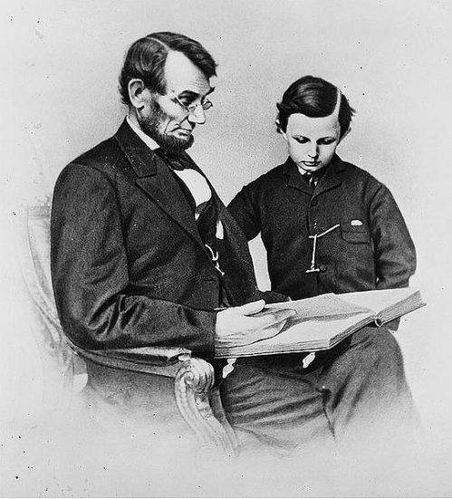 President Abraham Lincoln reading a book with his last son, Thomas (Tad) Lincoln.